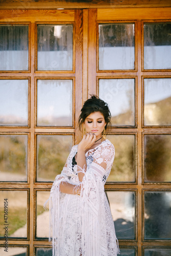 Young woman in lace dress stands near glass door
