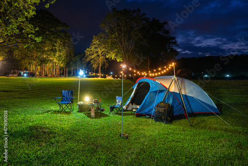 Camping tent and outdoor kitchen equipment at night in the park.