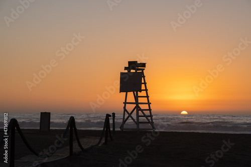 Silhouette of a lifeguard chair on a beach during sunset