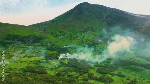 The drone flies over the Chornohora ridge and Lake Nesamovite, many colored tents on the Independence Day. Mount Turkul and Hoverla, copter aerial video photo