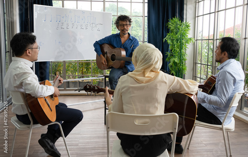 Music teacher teaching guitar to students in classroom