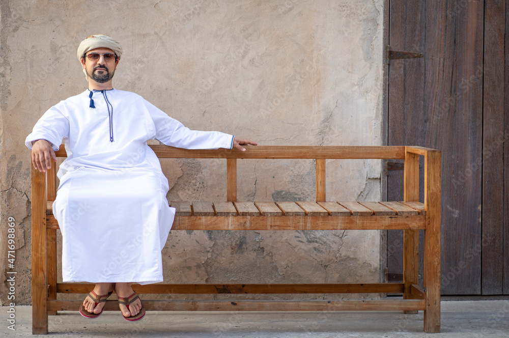Arab Man in Al Seef district in dubai seating outside his shop and enjoying the good weather