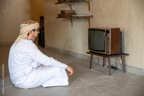 Arab man watching a vintage TV in al seef district in Dubai photo