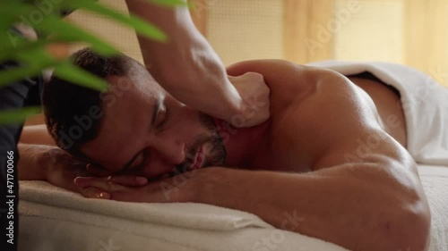 Close-up on a young man receiving a professional back massage
