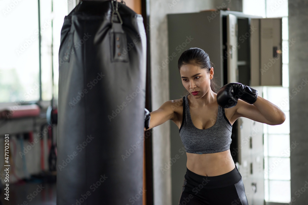 Female boxer punch sand bag in fitness gym