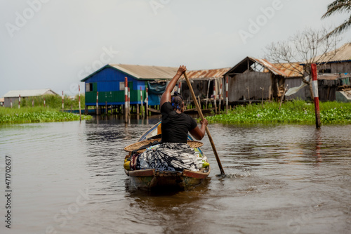 Woman rowing in Ganvié, Benin on Lake Nokoue. She has a large load of fruit she's going to sell at the market. photo