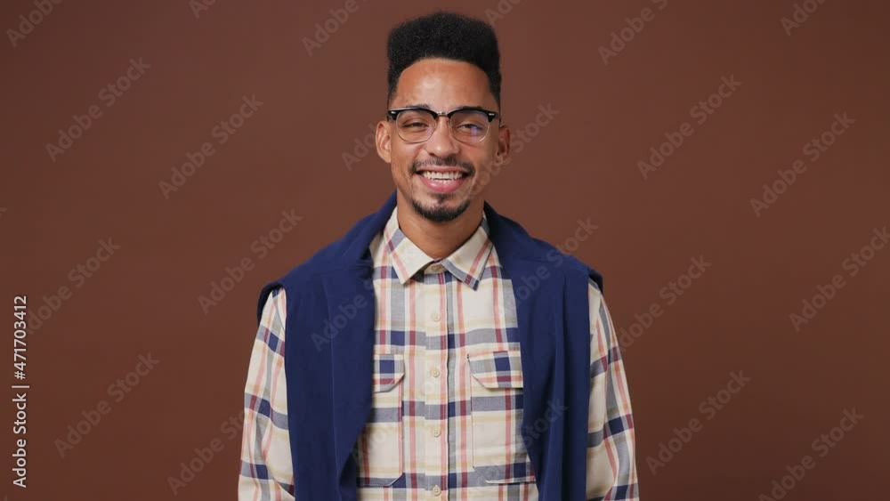 Smiling charming amazing marvelous cheery magnificent young african american man 20s wears striped shirt glasses looking camera wink eye blink isolated on plain dark brown background studio portrait Smiling charming amazing marvelous cheery magnificent young african american man 20s wears striped shirt glasses looking camera wink eye blink isolated on plain dark brown background studio portrait