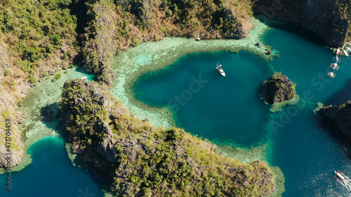 Fototapeta Naklejka Na Ścianę i Meble -  Aerial view tourist boats in lagoon. Kayangan Lake. lagoons, mountains covered with forests.coves with blue water among the rocks. Seascape, tropical landscape. Palawan, Philippines