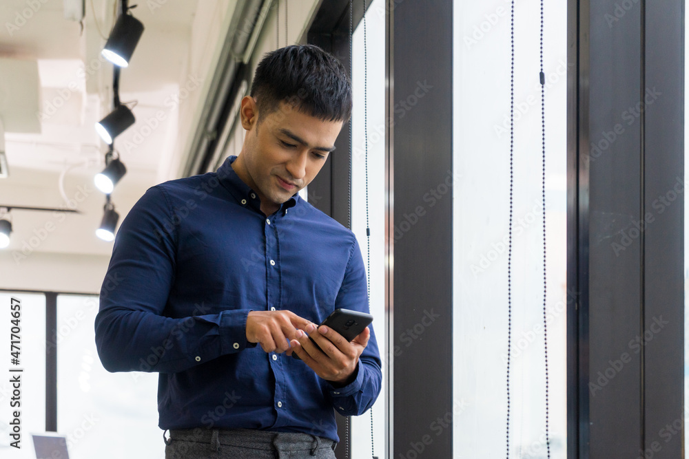 Young businessman executive using smart phone on window with city building background. Young businessman executive using smart phone on window with city building background.