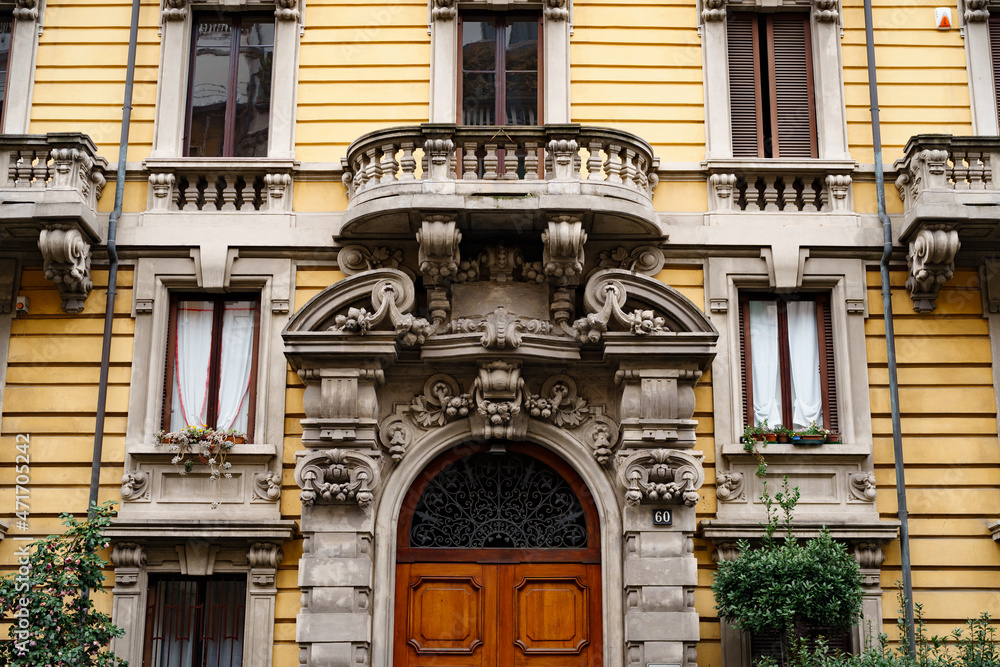 Central entrance to the old building with stucco and balconies. Milan, Italy