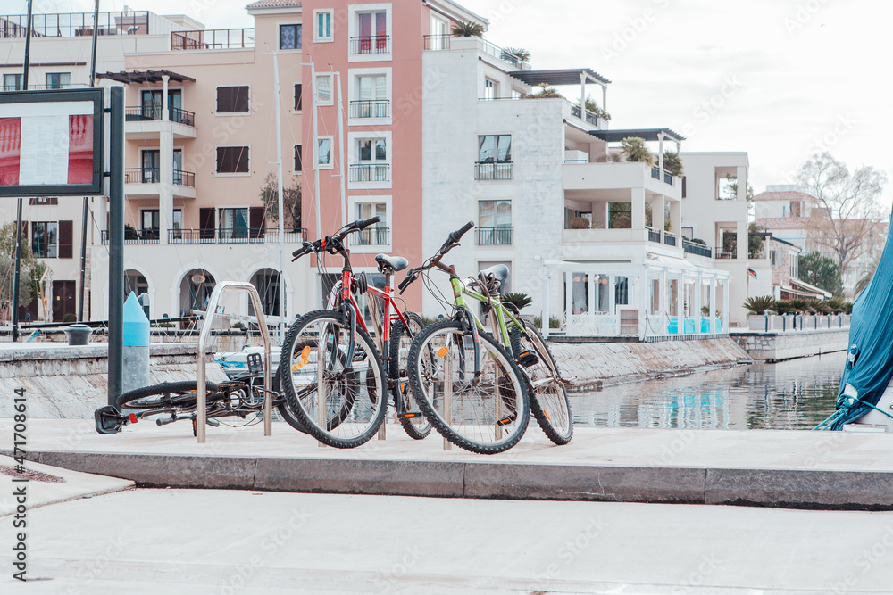 Bicycles are parked on the embankment. Bicycle parking in the background of modern houses. Urban backdrop for branding, banner, cover, card, poster, header for website. High Quality Horizontal Photo
