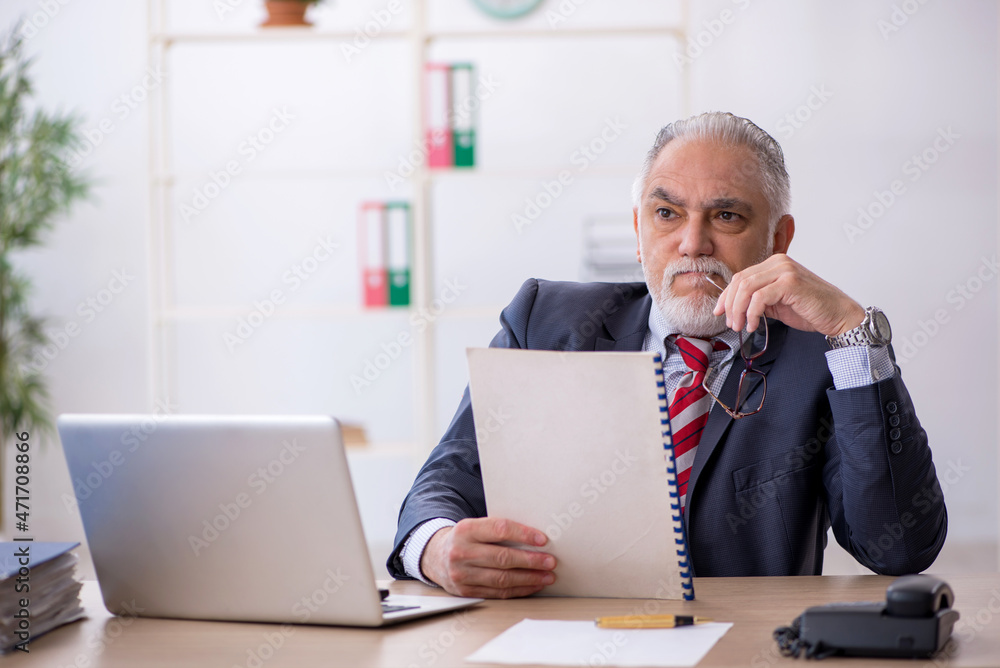 Old male employee working in the office Old male employee working in the office