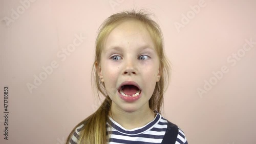 A beautiful five-six-year-old girl shows her mouth with fallen milk teeth.She smiles and grimaces.