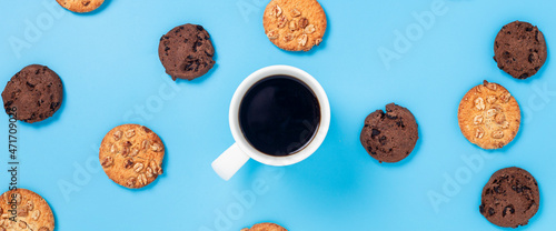 Cup of coffee, cookies on a blue background. Top view, flat lay. Banner. © Alex