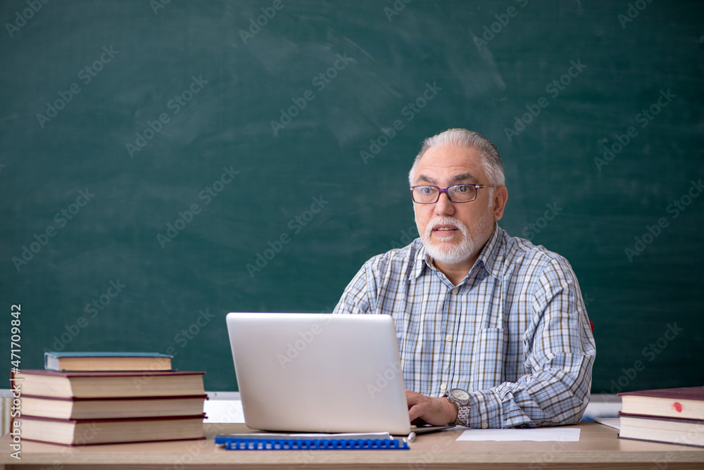 Old male teacher in the classroom Old male teacher in the classroom