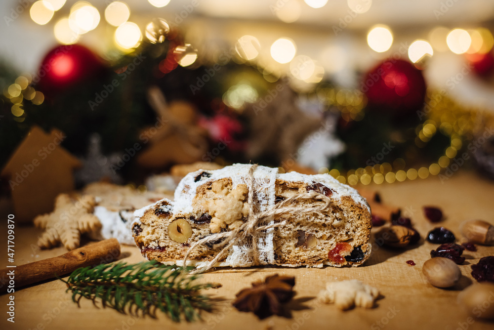 Christmas Stolen on wooden background. Traditional Christmas German, festive dessert. Christmas stollen cake with dried fruits, ginger cookies on the background of the Christmas tree. Selective focus