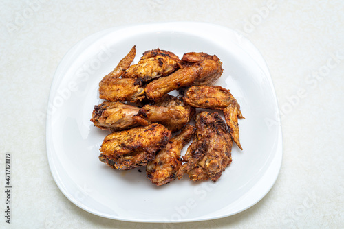 Freshly cooked crispy grilled chicken pieces on a white plate.