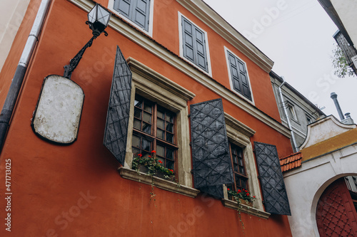 Orange wall with wooden windows. Window with shutters on a red wall. Orange house with windows and lanterns in tourist center of aEuropean city. photo