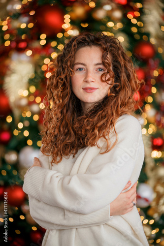 A beautiful red-haired girl portrait in a Christmas interior. Christmas theme. Cozy atmosphere. Christmas tree, decorated fireplace, lots of gifts, 