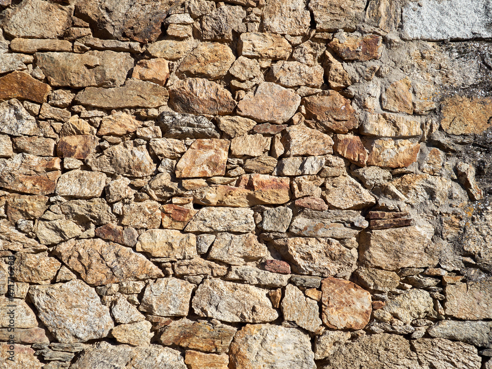 Natural rustic textured brown background. Wall made with piled stones Natural rustic textured brown background. Wall made with piled stones