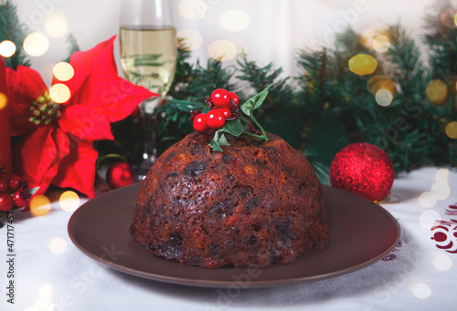 Traditional Christmas pudding with holly on top on the wooden background