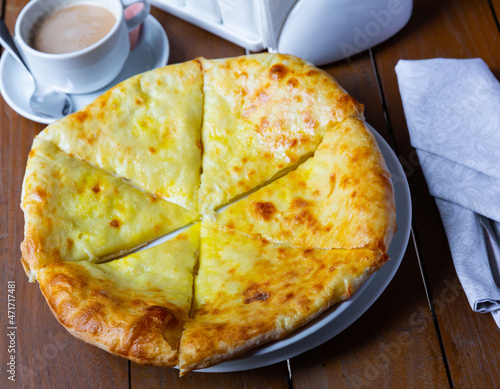 Traditional Georgian dish khachapuri Iveria, covered with suluguni cheese and cut into pieces photo