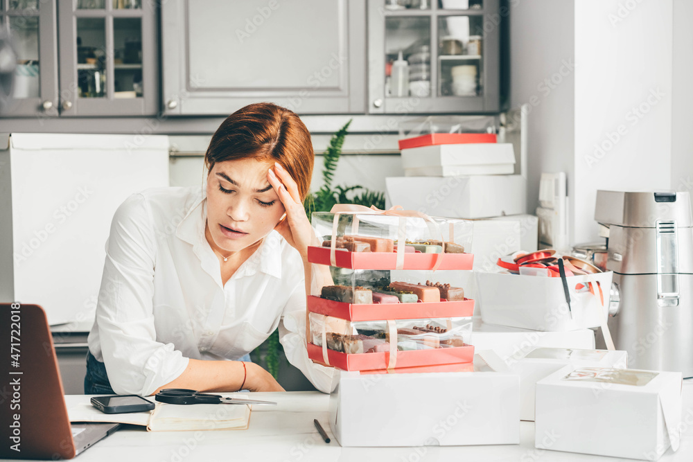 Process of packing cookies into a cardboard kraft box. Woman feeling bored, frustrated and sleepy after work. Small business owner. Process of packing cookies into a cardboard kraft box. Woman feeling bored, frustrated and sleepy after work. Small business owner.