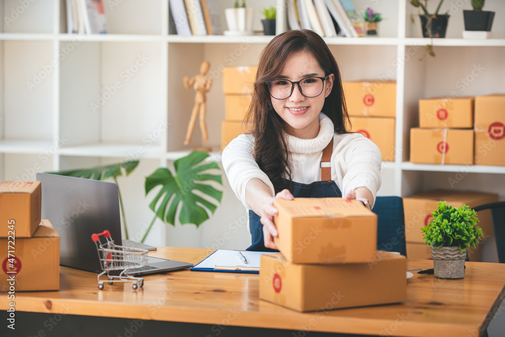 Small start-up business owners using computers at work, freelancers, saleswoman, checking production orders. Pack products for delivery to customers Small start-up business owners using computers at work, freelancers, saleswoman, checking production orders. Pack products for delivery to customers
