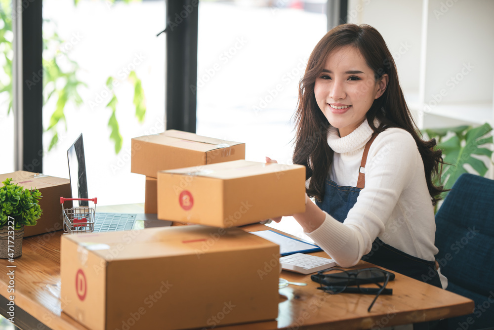 Small start-up business owners using computers at work, freelancers, saleswoman, checking production orders. Pack products for delivery to customers Small start-up business owners using computers at work, freelancers, saleswoman, checking production orders. Pack products for delivery to customers