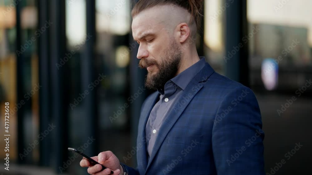 portrait of modern stylish businessman near entrance in his office building, using smartphone portrait of modern stylish businessman near entrance in his office building, using smartphone