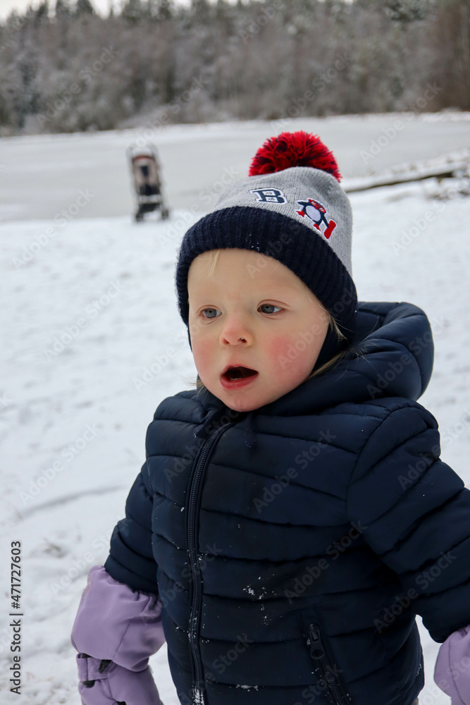 happy small child infant playing in snowy winter day