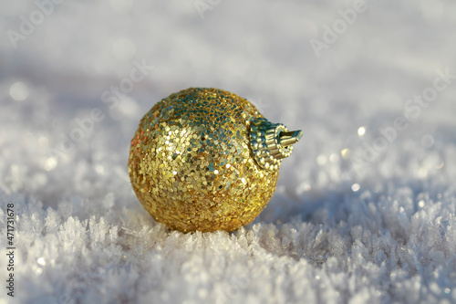 festive toy golden christmas ball lies on snow crystals in the new year's park