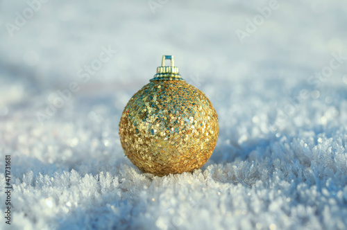 festive toy golden christmas ball lies on snow crystals in the new year's park