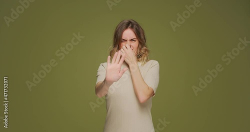 Bad smell and stop gesture. Woman pinching her nose with fingers feel disgusting odor, stink, having aversion photo