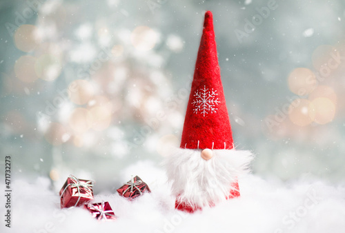 Christmas gnome greeting card with bokeh lights and snow, winter season, gift on the sledge