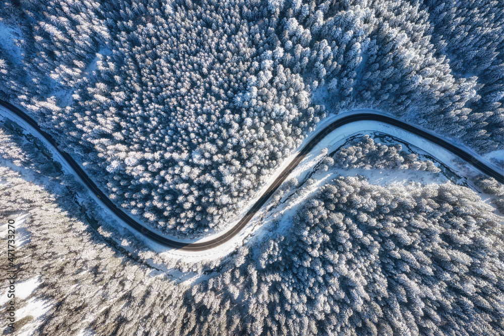 Natural winter landscape from air. Aerial view on the road and forest at the winter time. Winter chill. Forest and snow. The photo is in high resolution.