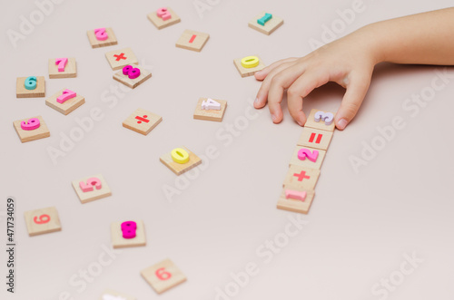 Five year old child learn learns arithmetic using a set of wooden numbers