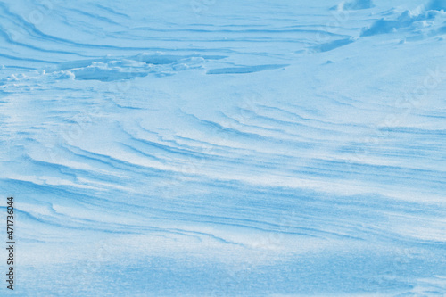 Snowy background, snow-covered surface of the earth after a blizzard in the morning in the sunlight with distinct layers of snow