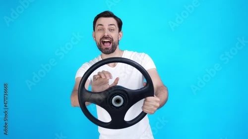 Positive guy begginer ride steering wheel isolated on blue color background photo