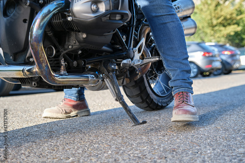 Close view shot of motorcyclist positioning the kickstand