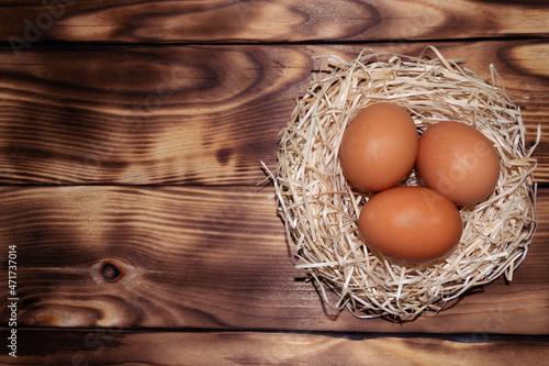 Easter brown eggs in the nest on a wooden background