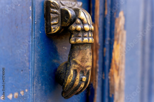 Kołatka w kształcie ręki, stara, ozdobna montowana na drzwiach.