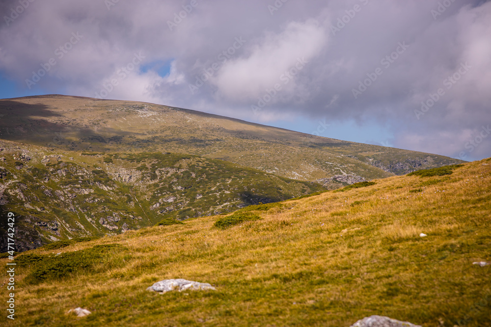 Bulgarian landscape of a mountain peak in Rila mountain.Beautiful nature landscape.Green grass and blue sky with clouds. High quality photo
