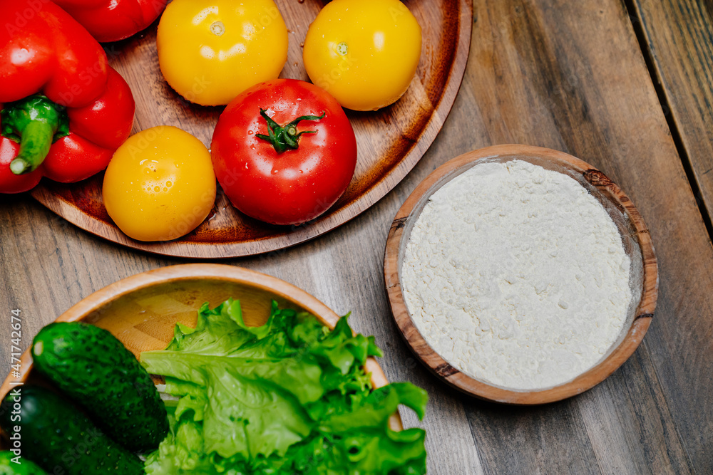 a wooden utensil with flour and vegetables on the kitchen table. a wooden utensil with flour and vegetables on the kitchen table.