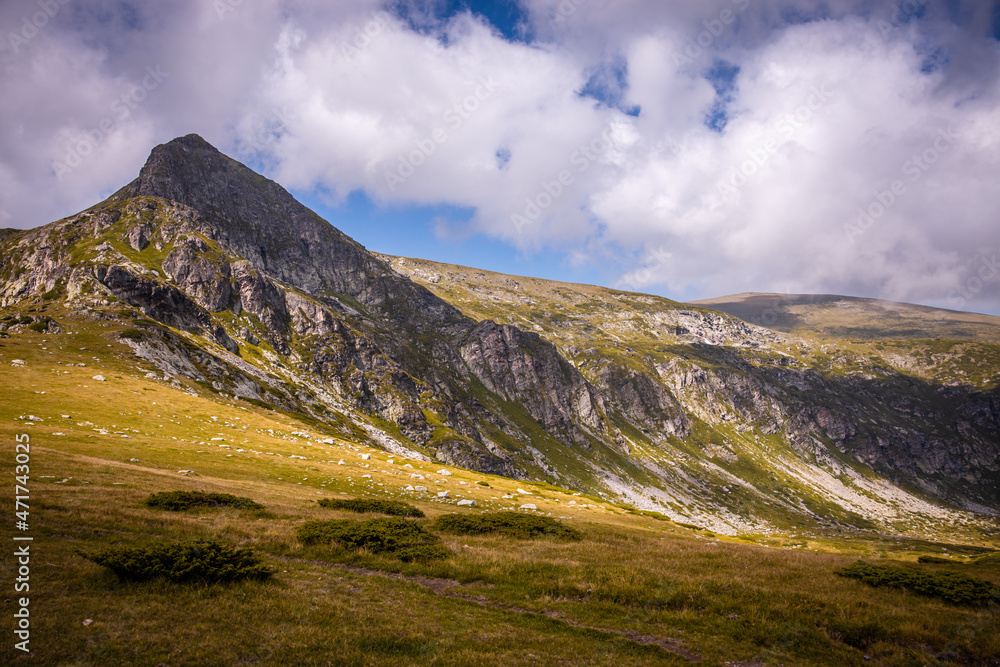 Bulgarian landscape of a mountain peak in Rila mountain.Beautiful nature landscape.Green grass and blue sky with clouds. High quality photo