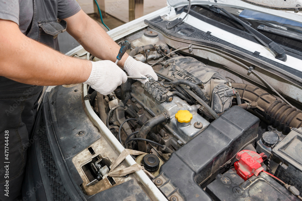 Mechanic repairing engine on a car using wrench. Close up of hands Mechanic repairing engine on a car using wrench. Close up of hands