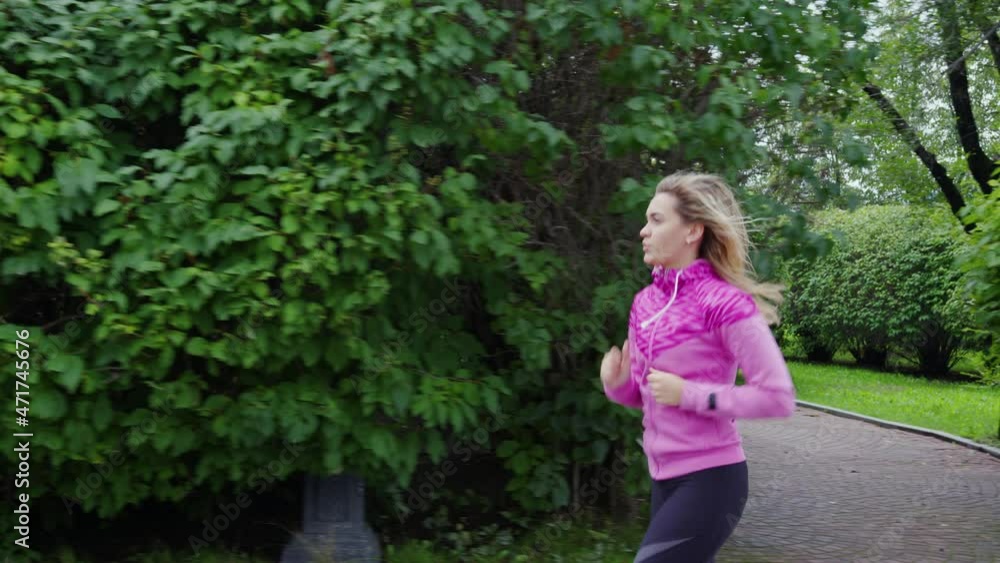 Fit girl runs along city park. Beautiful blonde doing warm-up, cardio workout outdoor. Sportswoman jogging at urban parkway. Young woman burn extra calories in morning Fit girl runs along city park. Beautiful blonde doing warm-up, cardio workout outdoor. Sportswoman jogging at urban parkway. Young woman burn extra calories in morning