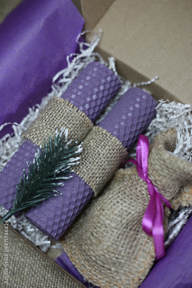 Gift box with a pair of purple beeswax candle on the rustic background. Two natural bio wax candles as a decoration for home interior.