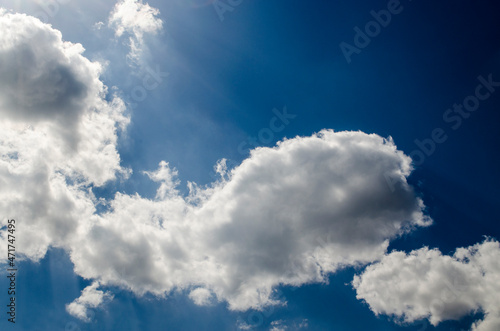 Blue sky with white clouds in sun rays. White fluffy cloud over summer sky background