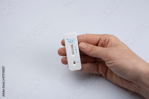 isolated shot of a right hand holding a negative result rapid express antigen coronavirus covid-19 pandemic test sample on a white background